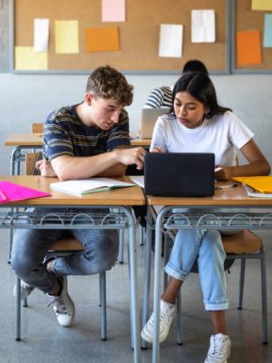 istockphoto-2065410888-612×612 Caucasian teen boy and native american teenage female high school students in class working together on school project using laptop. Vertical image. Education concept.